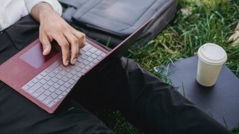 Mann på gress skriver på laptop